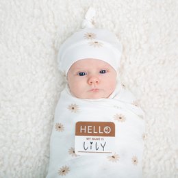 This swaddle and hat set features a soft, white fabric with a delicate daisy print. The swaddle is designed to gently wrap and soothe newborns, while the matching hat provides warmth and style. The set is perfect for welcoming a new baby into the world.
