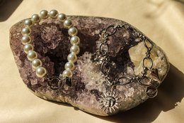  A bracelet with a variety of beads and charms, including pearls, crystals, and a central decorative element.