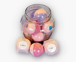 Assorted bath bombs in a glass jar, including lavender and rose scented varieties.