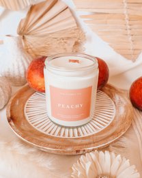 Peach-scented candle, peachy orange color, white wax, glass jar, natural aesthetic, fruity fragrance.