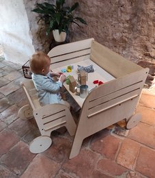 Wooden Montessori table and chair set with wheels, suitable for young children's play and learning. Features a sturdy, natural wood design with ample space for toys and activities.