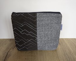 A gray and black toiletry bag with a geometric pattern and a textured fabric design.