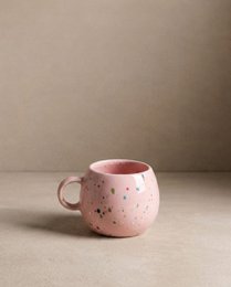 Pink speckled ceramic mug with a round, bulbous shape and a handle. Suitable for hot beverages.