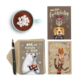 A set of 3 Christmas greeting cards featuring whimsical illustrations of animals wearing festive attire. The cards are accompanied by a mug of hot chocolate with marshmallows.
