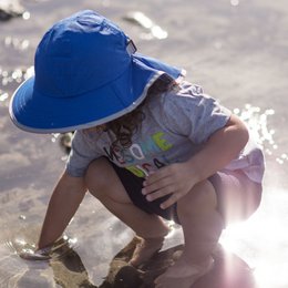 A blue sun hat with UPF 50+ protection for kids. The hat has a wide brim and adjustable chin strap to keep it securely in place. It is suitable for ages 6-24 months, 2-5 years, and 5-9 years.