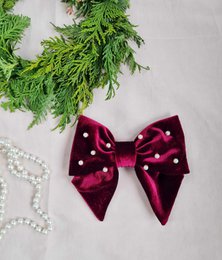 Burgundy velvet bow with pearl accents, perfect for adding a touch of elegance to any hairstyle.