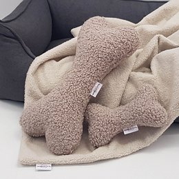 Plush bone-shaped pet toy in two sizes, S (20cm) and XL (40cm), made of soft, beige-colored sherpa material.