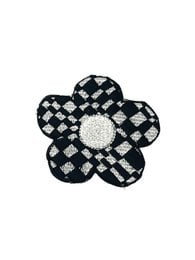 Flower-shaped brooch with black and white checkered pattern and a pearl-like center.