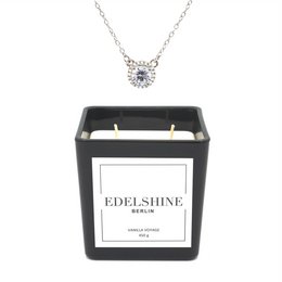 A large, scented candle with a classic necklace featuring a butterfly pendant.