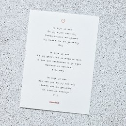 A white greeting card with a handwritten love poem in red text. The card has a small heart symbol at the top.