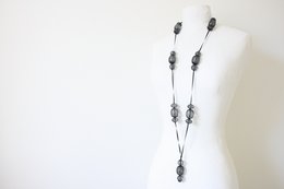 Long black necklace with oval-shaped beads and metal accents.