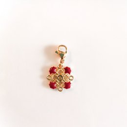 Burgundy-colored pendant with a floral design featuring red gemstones and a gold-toned metal frame.
