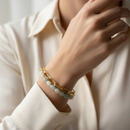 Gold-toned bracelet with aquamarine-colored beads, featuring a layered, textured design.