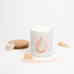 A tall, round white soy candle with a sea-inspired flame icon and wooden lid. The candle has a 'Sea Walk' scent.