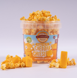 Cheddar cheese flavored popcorn in a clear plastic container. The popcorn is bright orange in color and appears to be coated in a cheddar cheese seasoning. The container is labeled "Cheddar Cheese" and features an image of a smiling cartoon character.