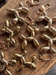 Gold balloon dog-shaped keychains on a wooden surface.