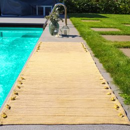 Yellow yoga mat with textured surface, suitable for indoor or outdoor use near a swimming pool.