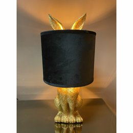 A decorative table lamp with a golden hare-shaped base and a black fabric shade.