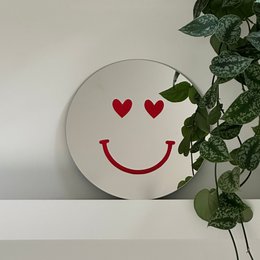 Round wall mirror with a red smiley face and hearts, perfect for adding a cheerful touch to any room.