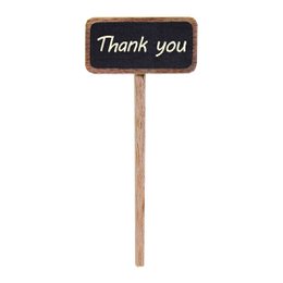 A small chalkboard sign on a wooden stick, displaying the text "Thank you". The sign is placed in a small white ceramic pot, held in a hand against a blurred green background.