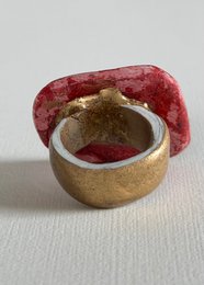 Red textured resin statement ring with gold metallic base, bold sculptural design.
