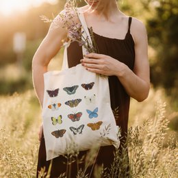 A cotton tote bag featuring a colorful collection of butterfly illustrations. The bag is suitable for shopping or everyday use.