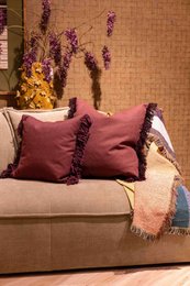  Decorative cushion with plush burgundy fabric and fringe trim, ideal for living room or bedroom decor.