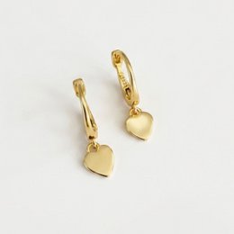  Hoop earrings with heart pendant, available in gold and silver. The earrings feature a circular hoop design with a heart-shaped pendant charm.