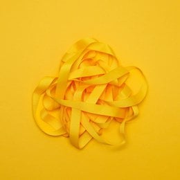 A bright yellow ribbon with the text "MY PRETTY CIRCUS" printed on a black label. The ribbon appears to be made of a soft, satin-like material and is coiled in a decorative manner.