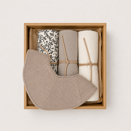  A gift box containing soft, cozy items in shades of yellow and beige. The box is made of cardboard and features a simple, nature-inspired design with silhouettes of animals.