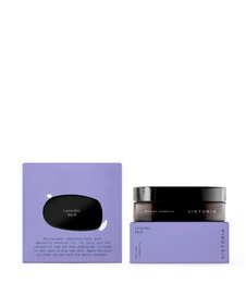 Lavender-scented balm in a black jar with a purple label. The balm appears to be a soft, creamy texture and is likely made with natural ingredients.