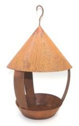 A round, wooden birdhouse on a stick with an orange, cone-shaped roof. The birdhouse has a perch and a small opening for birds to enter.