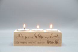 A wooden candle holder with the text "Keep a little light in your heart" and three lit candles.