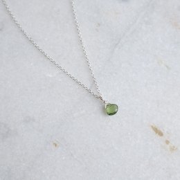 A delicate green apatite gemstone pendant on a silver chain. The pendant has a simple, minimalist design that would complement a variety of outfits.