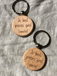 Wooden keychain with the text "Je suis précieux good" (I am precious good) in a simple, rustic design.