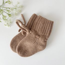 Cozy brown merino wool slippers with ribbed texture and tie detail.