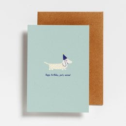 A colorful birthday card featuring a playful dog illustration and the text "Happy birthday, you animal!". The card has a mint green background and a brown envelope.