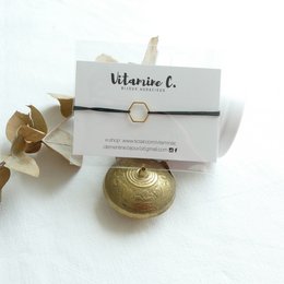 Black and gold charm bracelet with a round, textured charm.