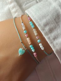  Colorful beaded bracelets with gemstone accents in silver, gold, and rose gold tones. Features a mix of turquoise, pink, and white beads for a stylish and versatile accessory.