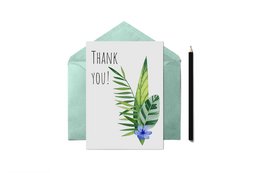 A thank you card with a floral design featuring green leaves and a purple flower. The card is placed on a white background with additional leaves scattered around.