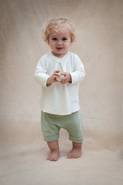 Baby shorts in ecru, light brown, dark brown, and light green colors. Sizes range from 3 months to 24 months. The shorts have a simple, casual style.