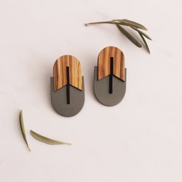 Oval-shaped statement earrings made of cellulose acetate in a combination of wood-like and matte black tones. Features a unique geometric design with contrasting materials.