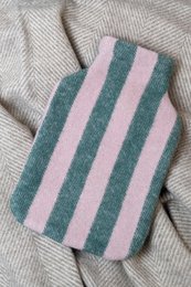 Striped hot water bottle cover in green and pink colors, made of soft, cozy material for baby's comfort.