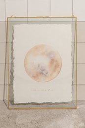 A framed poster featuring a circular abstract design in neutral tones.