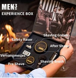 A men's grooming experience box containing a safety razor, shaving cream, after-shave, and a shaving brush. The box is designed for a premium beard care experience.