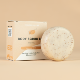 Exfoliating body scrub bar made with natural ingredients. Oval-shaped, white with brown speckles. Provides gentle exfoliation and nourishment for the skin.