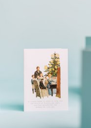 A greeting card depicting a grandfather sleeping in a chair next to a Christmas tree, with a family gathered around him.