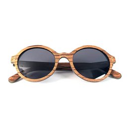 Wooden solar glasses with a round, oval shape in three color variants: Zébrano, Noyer, and Palissandre. The glasses feature a classic, stylish design with a wooden frame and dark tinted lenses.