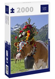 A 2000-piece puzzle depicting a cow wearing a traditional Bavarian-style headdress adorned with flowers, fruits, and other decorative elements. The cow is standing in a grassy field with mountains in the background.