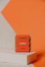 Orange exfoliating body scrub with lime scent. Rectangular bar with textured surface.